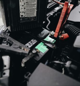Detailed view of a car battery being jump-started with cables in an engine bay.
